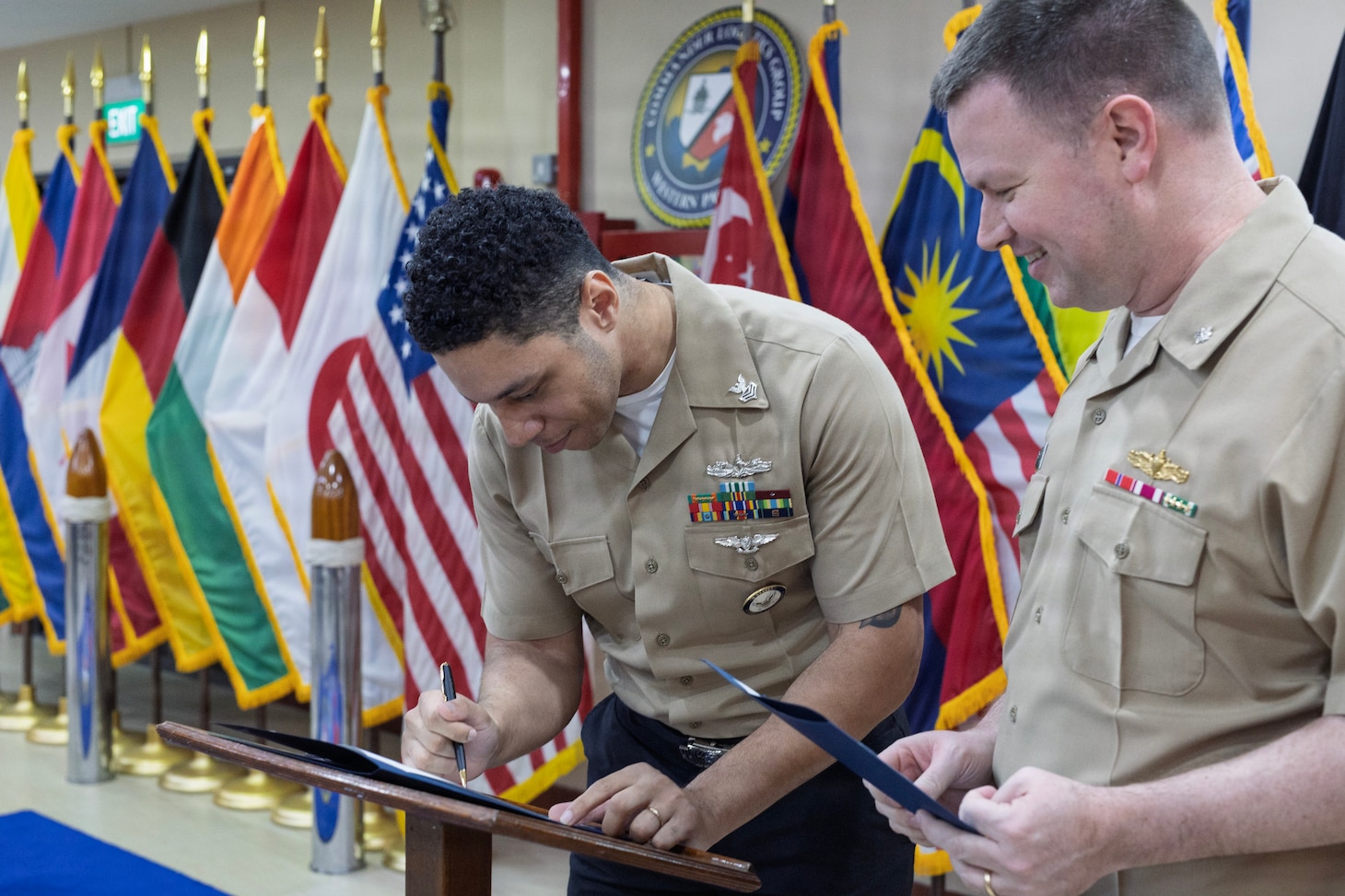 Yeoman 1st Class Robert J. Carter, administrative officer assistant, Military Sealift Command (MSC) Far East, signs re-enlistment documents prior to his re-enlistment ceremony at MSC Far East headquarters, Singapore Naval Installation, Singapore, Feb. 26, 2026.