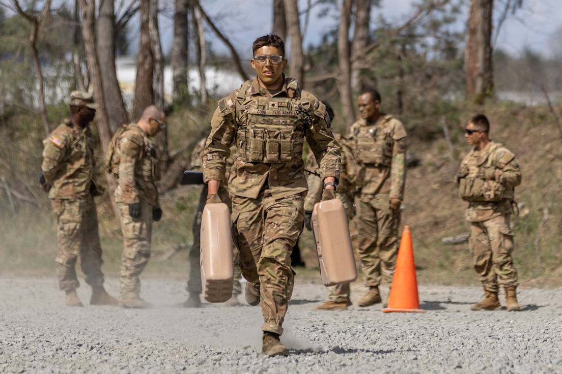 Spc. Jozef Cobb, a wheeled vehicle mechanic, representing the 16th Sustainment Brigade, 21st Theater Sustainment Command, runs while carrying jerry cans of full water during day five of the 21st Theater Sustainment Command Best Squad Competition on U.S. Army Garrison Bavaria, Grafenwoehr, Germany.