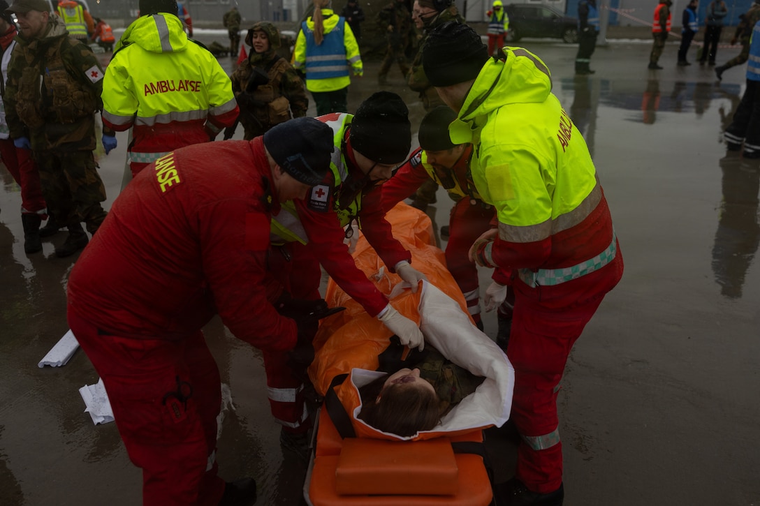 Civilian emergency response organization personnel secure a simulated casualty to a gurney at Breivika Harbour in Tromsø, Norway, March 12, 2026. Emergency responders secured the simulated casualty before transporting them to the ambulance during a simulated mass-casualty reception exercise as part of exercise Cold Response 2026. During the scenario, approximately 80 to 100 role players acting as casualties arrived by vessel from a simulated “northern front” and were received by military and civilian responders operating within Norway’s total defense framework. Personnel conduct casualty reception, triage and coordinated transport operations before moving patients to University Hospital of North Norway for follow-on treatment. The exercise demonstrates cooperation between the Norwegian Armed Forces, allied partners and civilian agencies and aims to increase public understanding of the importance of Norway’s total defense system while strengthening coordination for large-scale emergency and wartime medical response. (U.S. Marine Corps photo by Lance Cpl. Franco Lewis)
