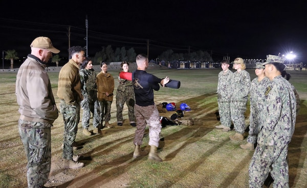 Staff Sgt. Joshua Hutchinson (center) demonstrates pugil sticks technique and handling to Sailors assigned to Navy Medicine Readiness and Training Command Twentynine Palms during a Marine Corps Martial Arts Program Tan Belt course at Marine Corps Air Ground Combat Center Twentynine Palms on Dec. 15, 2025. The training bolsters interoperability with Marines to provide war-ready medical care, increases lethality and reinforces the warrior ethos. (U.S. Navy photo by Christopher Jones, Navy Medicine Readiness and Training Command Twentynine Palms / Naval Hospital Twentynine Palms public affairs officer).