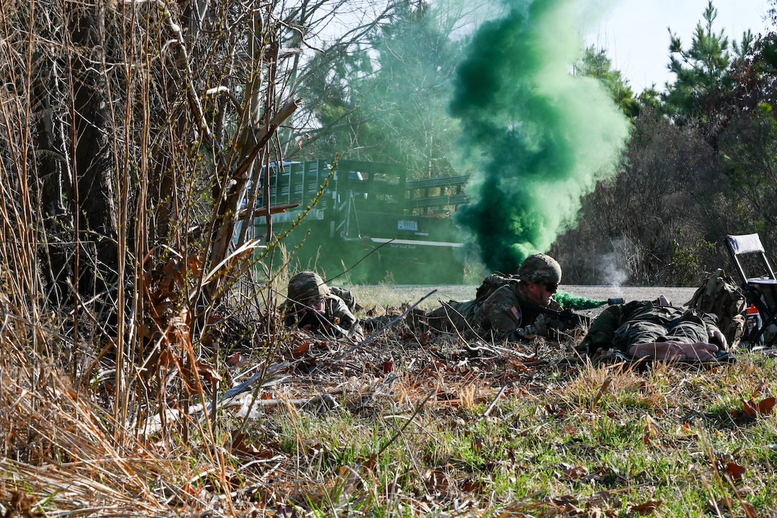 Soldiers lie on ground armed with replica weapons in front of camouflage gas. (U.S. Air Force photo by Airman 1st Class Donnell Ramsey)