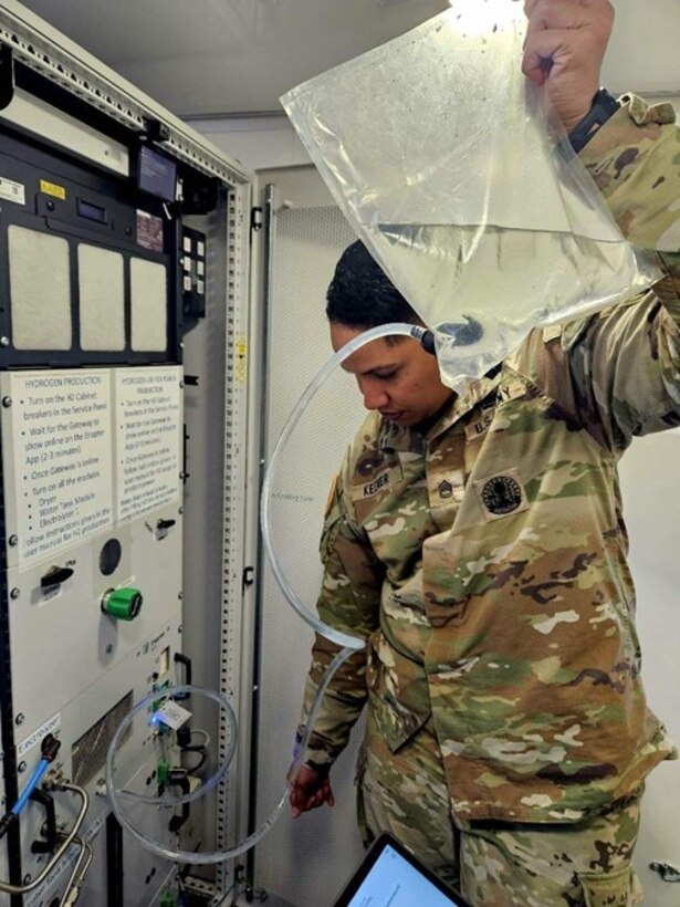 SFC Aileen Keemer, 1st Armored Division, Fort Bliss, Texas, fills the electrolyzer of the nanogrid with distilled water during the nanogrid training event at Fort Bliss.