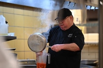 Mr. Cordell “Bo” Bomar, 5th Force Support Squadron Executive Chef, pours a prepared mixture into a container during an internal competition at the dining facility at Minot Air Force Base, North Dakota, Feb. 12, 2026. Mr. Bomar led both teams during the cook-off, offering direction and support as participants collaborated, refined their techniques, and developed new menu ideas. (U.S. Air Force photo by Airman Joseline Chacon Monterroso)