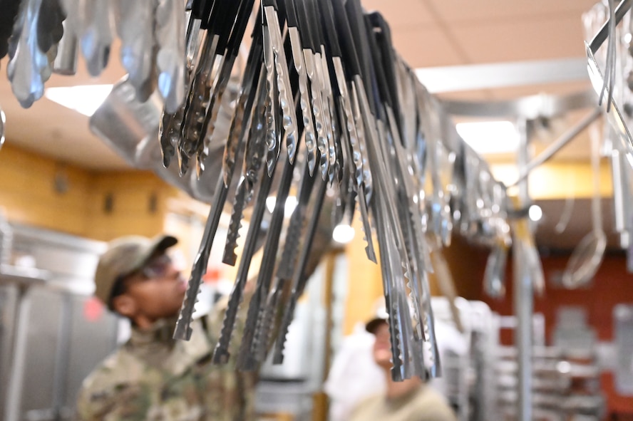 Serving tongs hang for use during an internal cooking competition at Minot Air Force Base, North Dakota, Feb. 12, 2026. Airmen assigned to the facility competed against one another to showcase their culinary skills and creativity while strengthening teamwork in the kitchen. (U.S. Air Force photo by Airman Joseline Chacon Monterroso)