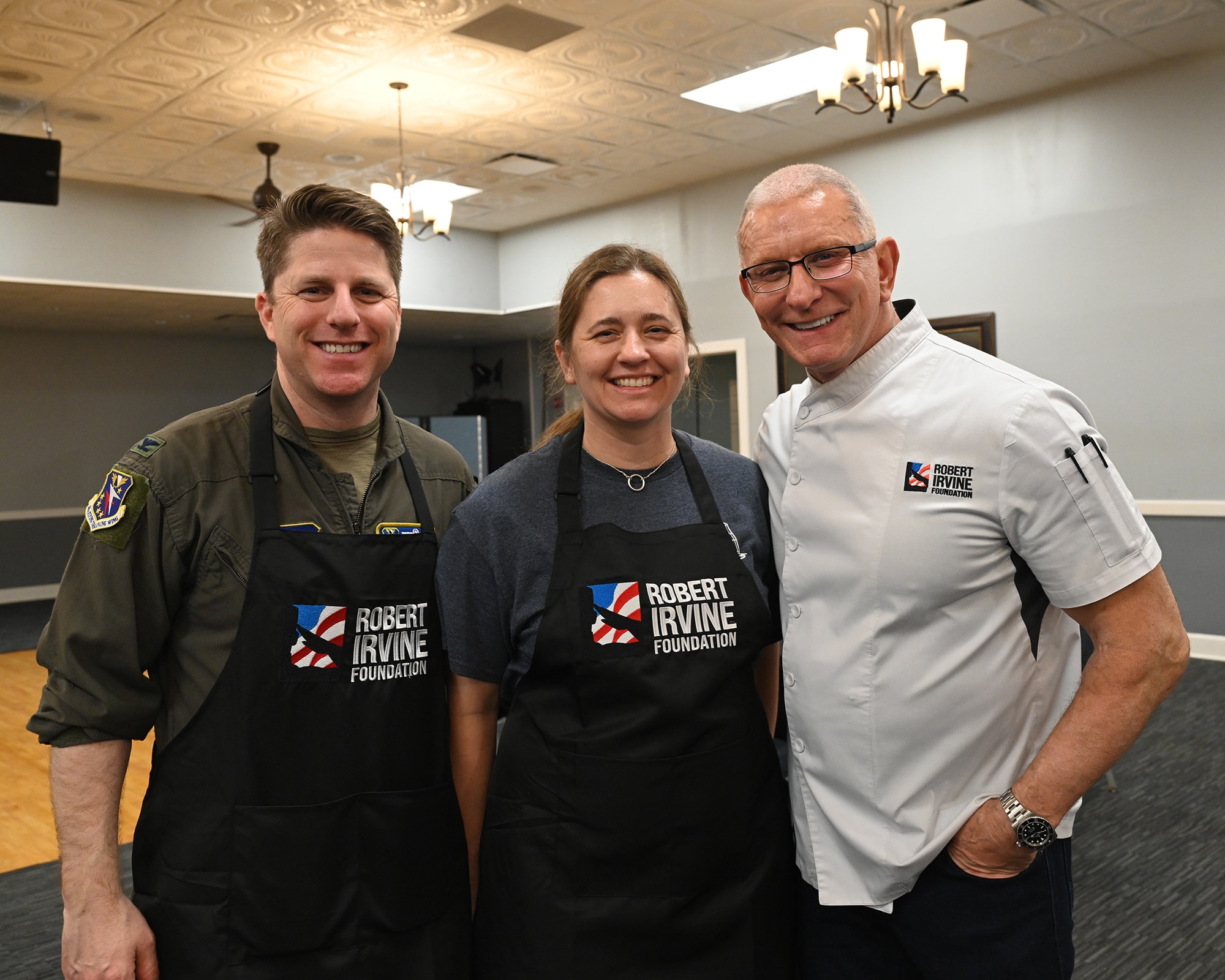 From left, U.S. Air Force Col. James Blech, 14th Flying Training Wing commander; U.S. Air Force Reserve Lt. Col. Stephanie Blech, Admission Liaison Officer; and Chef Robert Irvine, Robert Irvine Foundation founder, participate in a "Breaking Bread with Heroes" event at the Event Center on Columbus Air Force Base, Mississippi, Feb. 27, 2026.