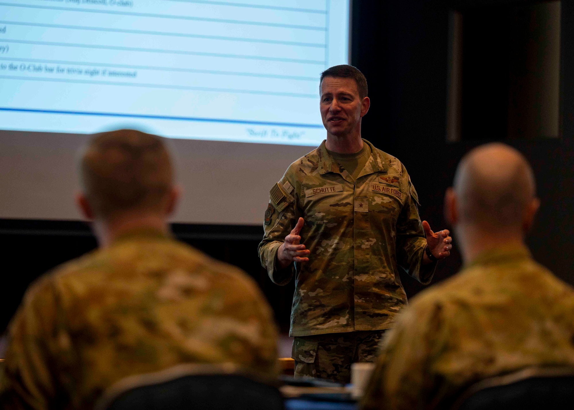 A military member speaks in front of a group of people.