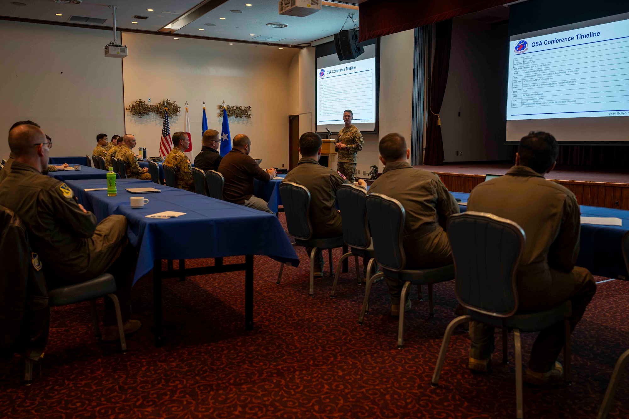 A military member speaks in front of a group of people.