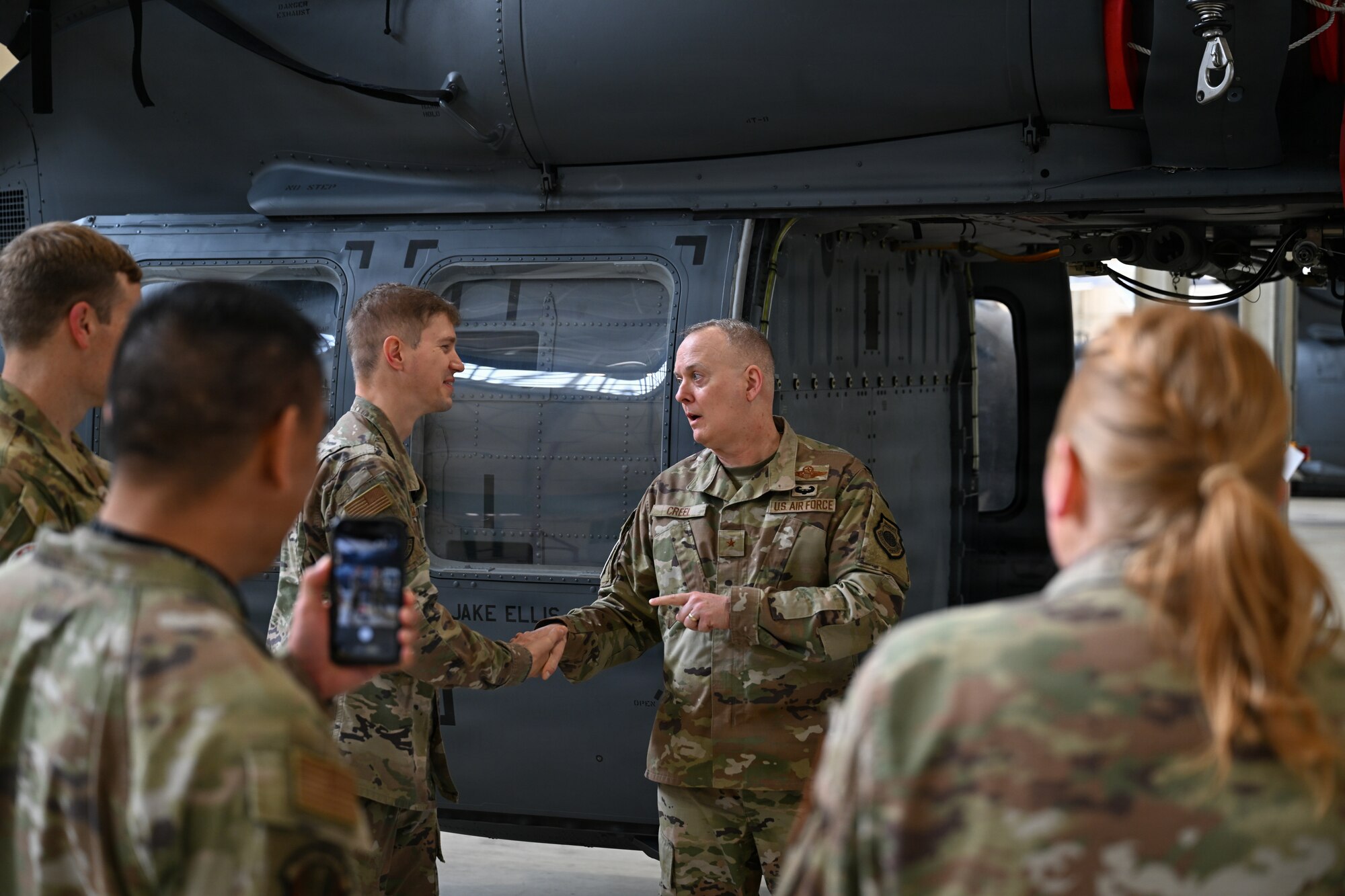 General Creel gives a coin to an airman.