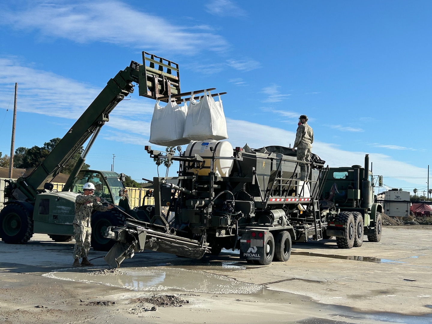 Men working with truck and construction equipment to pour rapid-setting .