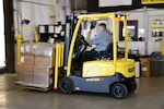 A man operates a forklift with boxes on the front