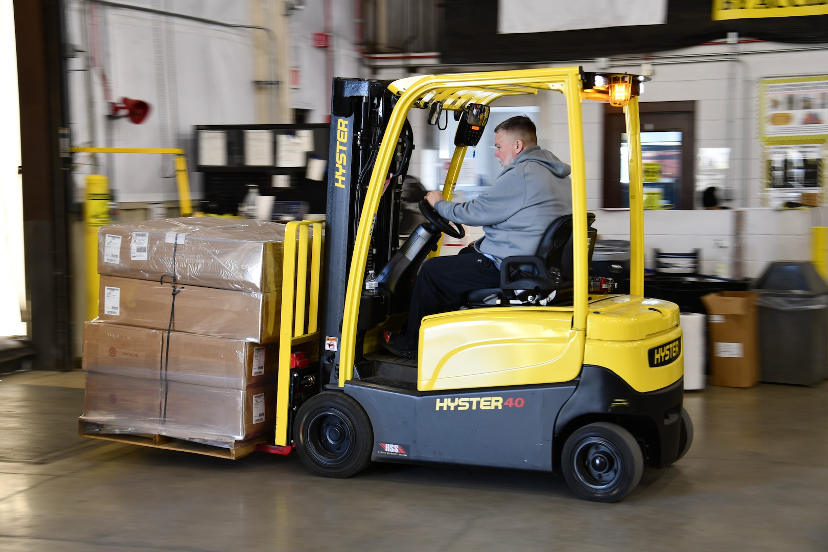 A man operates a forklift with boxes on the front