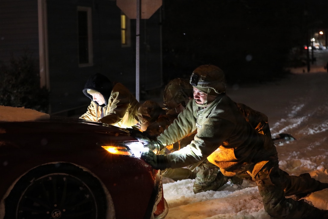 U.S Army Sgt. 1st Class Caleb Tidei, Sgt. 1st Class Ryan Wilhoit and Spc. Kyle Clark, all with the 63rd Theater Aviation Brigade, assist a vehicle who had gotten stuck on the roadway in Frankfort Kentucky, during Winter Storm Fern Jan. 26, 2026.