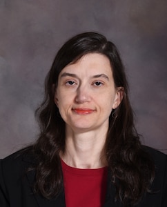 Christine Moritz faces the camera for her professional headshot, she is wearing a red shirt with a black blazer over top.