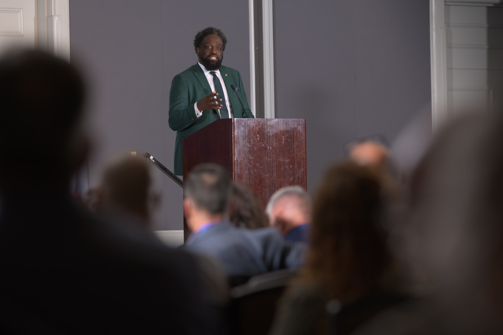 A man stands at a podium in front of an audience