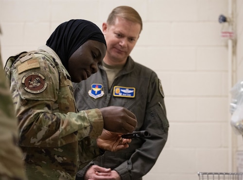 U.S. Air Force Senior Airman Ouswatoy Mamoudou Imorou, 97th Logistics Readiness Squadron individual protective equipment journeyman, left, demonstrates disassembling a weapon to Col. Richard Kind, 97th Air Mobility Wing commander, right, at Altus Air Force Base, Oklahoma, Feb. 25, 2026. Mamoudou led the 97th AMW command team through a simulation of issuing weapons for deployment and clearing them as well as illustrating the disassembling, reassembling and function-checking procedures. (U.S. Air Force photo by Airman 1st Class Emma Wright)