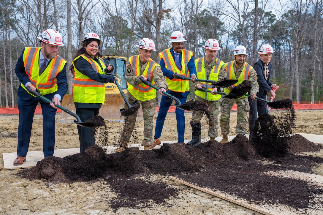 Joint Base Langley-Eustis installation leaders, community partners and project stakeholders lift a shovel in front of them after shoveling dirt.