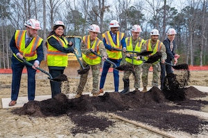 Joint Base Langley-Eustis installation leaders, community partners and project stakeholders lift a shovel in front of them after shoveling dirt.