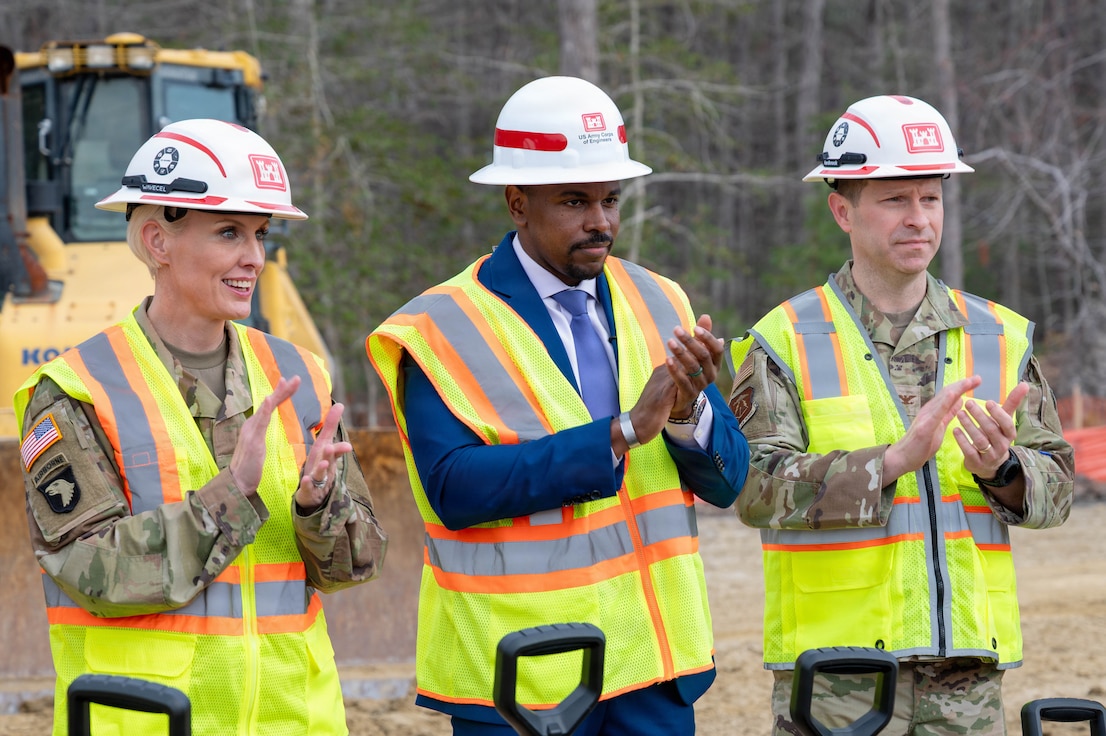 From left, U.S. Army Col. Laura Hutchinson, 733d Mission Support Group commander, Phillip Jones, mayor of Newport News and U.S. Air Force Col. Stephen Anderson, 633d Air Base Wing commander stand side by side clapping with hard hats on and yellow vests.