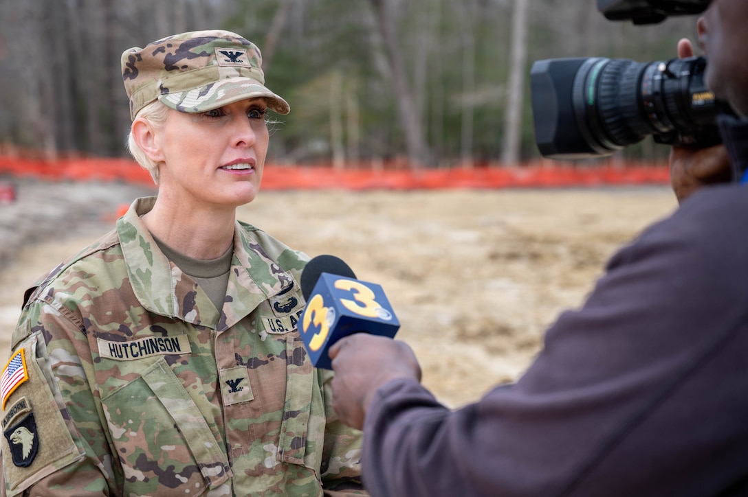 U.S. Army Col. Laura Hutchinson stands to the left in front of a camera being held by and interviewer.
