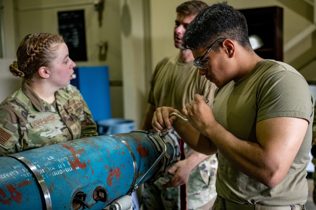 An airman tightens screws on a GBU-54 bomb