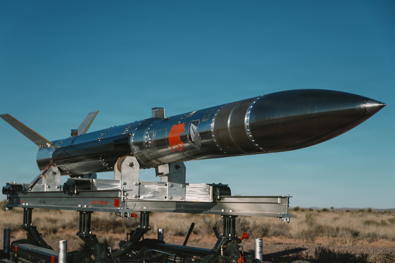 A missile sits on a trailer in a desert environment.