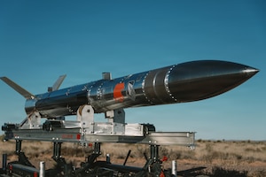 A missile sits on a trailer in a desert environment.