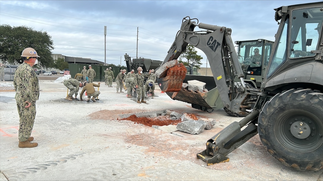 Men watching backhoes dig apart concrete.