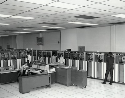 Data-processing personnel operate three IBM 7080 computers