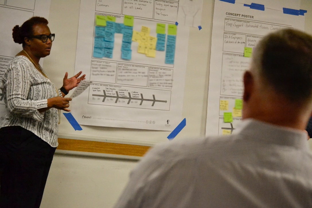 A woman stands next to a presentation poster on the wall
