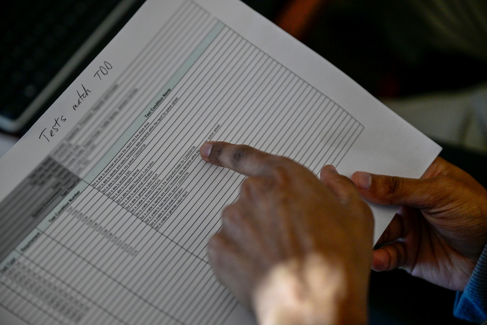 A close-up of a spreadsheet of test conditions with a finger scanning across a row