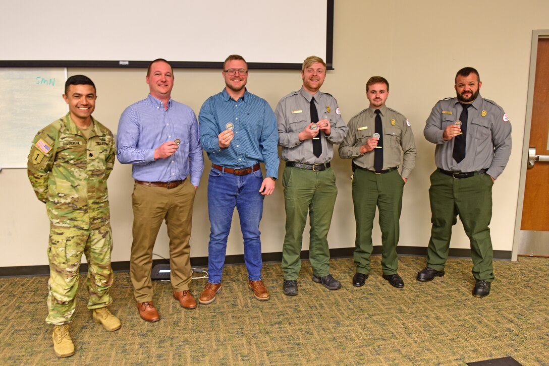 Lt. Col. Guillermo Guandique, U.S. Army Corps of Engineers Nashville District commander, recognizes the Noise Exposure Product Delivery Team March 10, 2026, that worked to find and test products, conduct noise sampling, and selected an innovative new device that provides active hearing protection to filter out harmful sounds for rangers that patrol on the lakes and are exposed to engine and wind noise. The commander lauded (Left to Right) John Malone, Daniel Rennaker, John Poston, Dylan Norton, and Lucas Hix March 10, 2026, during the annual Park Ranger Workshop at Chattanooga State Community College in Chattanooga, Tennessee. Ben Clark, not in photo, was also recognized. (USACE Photo by Lee Roberts)