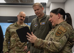 U.S. Air Force Staff Sgt. Heather Grigg, 97th Logistics Readiness Squadron (LRS) ground transportation support non-commissioned officer in charge, right, displays the AI virtual vehicle inspection courses to Col. Richard Kind, 97th Air Mobility Wing (AMW) commander, center, and Chief Master Sgt. Jonny Adams, 97th AMW command chief, left, at Altus Air Force Base, Oklahoma, Feb. 25, 2026. Grigg demonstrated the 97th LRS innovative approach to enhancing safety and mission-readiness through the Driving Simulator and AI vehicle inspection platform during a hands-on immersion tour with the 97th AMW command team. (U.S. Air Force photo by Airman 1st Class Emma Wright)