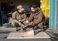Andres Martinez Murillo, lead biomedical engineer for Naval Medical Research Unit (NAMRU) San Antonio, explains stability testing on the novel SynDaver thermal, bleeding manikin thigh to U.S. Air Force Lt. Col. Kaitlin Salle at the Kodiak Coast Guard Clinic in Kodiak, Alaska during Arctic Edge 2026, Feb. 26. The novel manikin thigh is meant to keep the circulating ‘blood’ heated to normal body temperature so that researchers can see decompensation of bleeding while exposed to extreme cold. NAMRU San Antonio, part of Navy Medicine Research & Development, conducts gap-driven combat casualty care, craniofacial, and directed energy research in support of Navy, Marine Corps and joint U.S. warfighter health readiness and lethality while engaged in routine and expeditionary operations. (U.S. Navy Photo by MC1 Abigayle Lutz/Released)