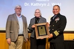 Kathryn Wahl (center), Ph.D., U.S. Naval Research Laboratory (NRL) Surface Chemistry branch head, receives the 2025 E.O. Hulbert Annual Science Award from Dr. Bruce Danly (left), NRL director of research, and CAPT Randy Cruz, NRL commanding officer, in Washington, D.C., March 6, 2026. Wahl received the award for her significant advances in measurement, observation, and understanding of interfacial contacts. (U.S. Navy photo by Sarah Peterson) RELEASED