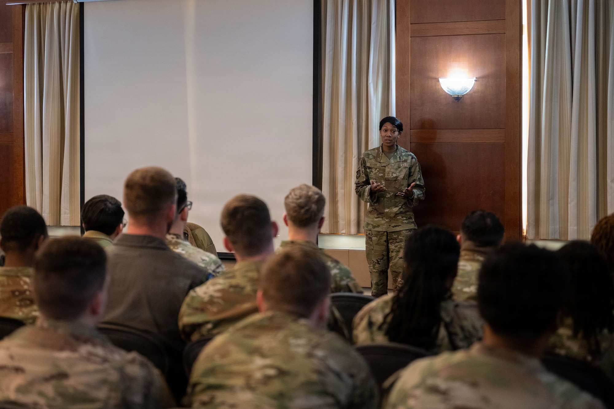 Airmen look at 89th Wing command chief in a conference room.