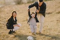Mother and father playing with their child in a yard