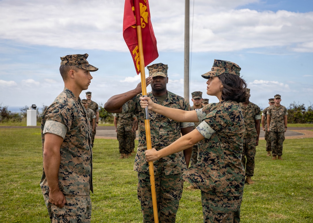 U.S. Marine Corps Capt. Danielle Eitel, right, the outgoing company commander with Headquarters Company, Headquarters and Service Battalion, U.S. Marine Corps Forces, Pacific, extends the guidon to Capt. Jordan Paine, left, incoming company commander for HQ Co., during the company’s change of command ceremony at Camp H.M. Smith, Hawaii, Feb. 27, 2026. During the ceremony, Eitel relinquished command of the company to Paine. (U.S. Marine Corps photo by Lance Cpl. Moses S. Lopez Franco)