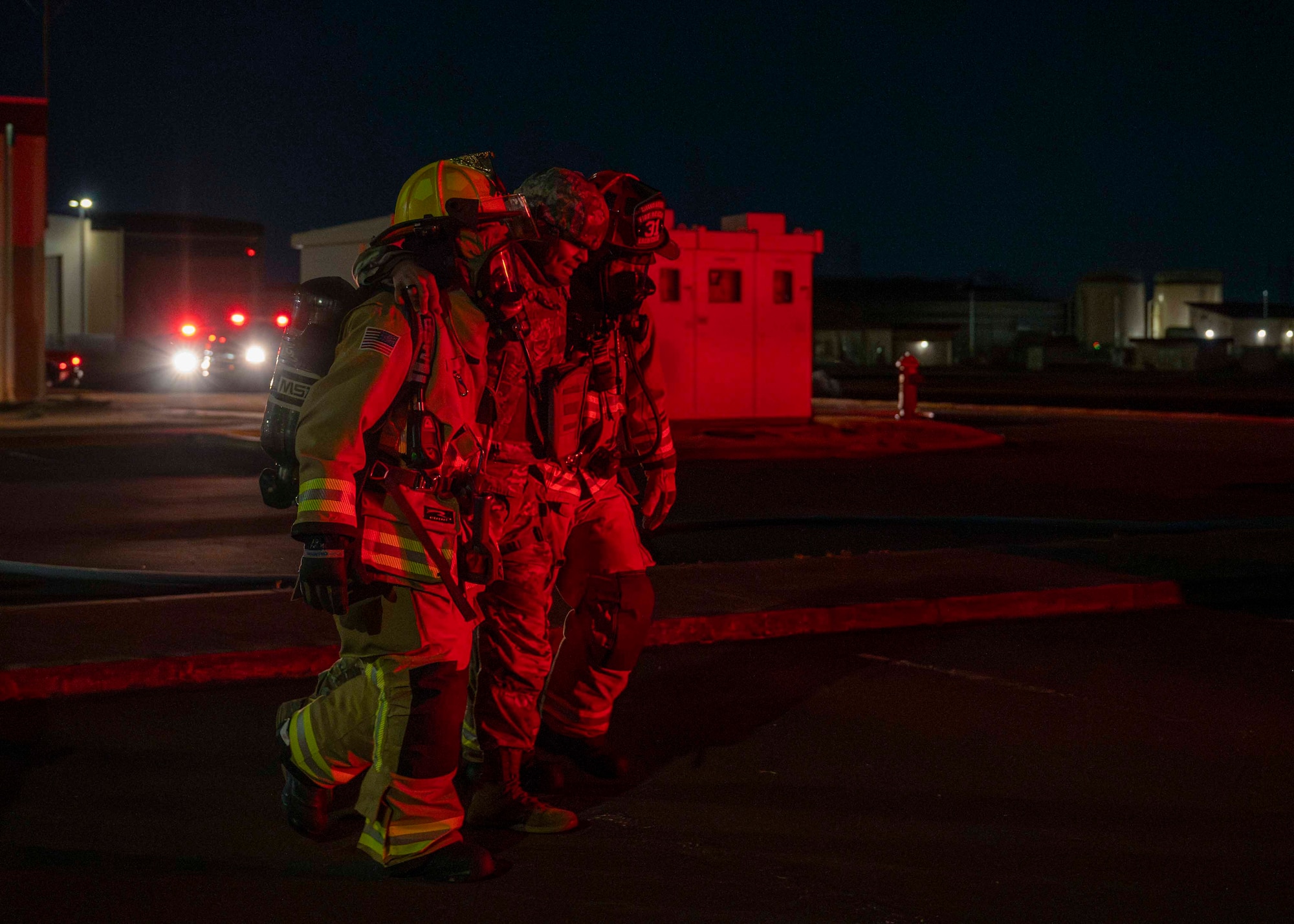 Two firefighters assist an Airman walk.