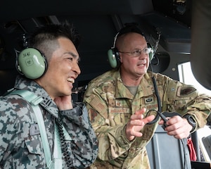A U.S. Air Force military member speaks to a Japan Air Self-Defense Force member inside an aircraft.