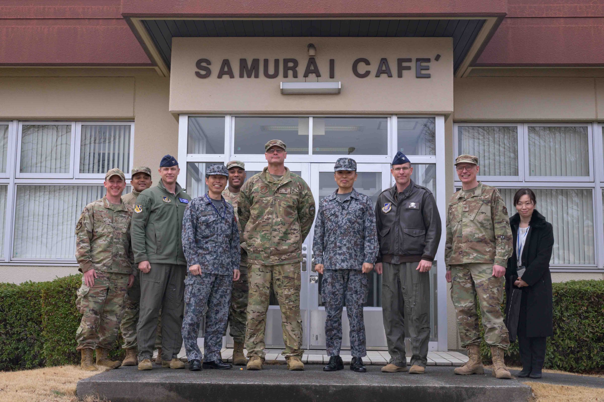 U.S. Air Force Airmen and Japan Air Self-Defense Force members pose for a group photo in front of a dining facility.