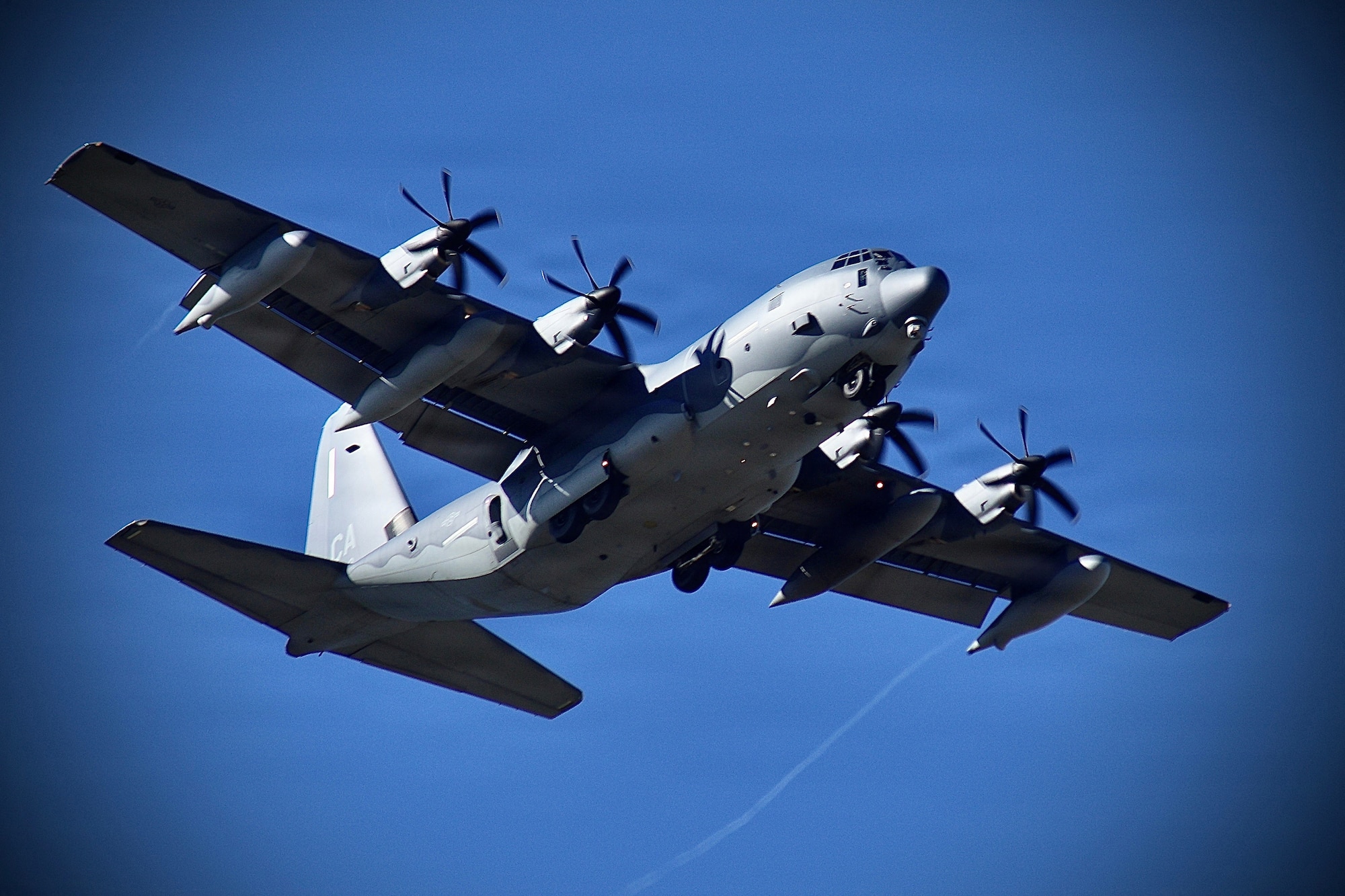 An aircrew with the 129th Rescue Wing, California Air National Guard, performs a fly-by of the airfield in an HC-130J Combat King II during a training mission at Moffett Federal Airfield, California, Aug. 2, 2025.