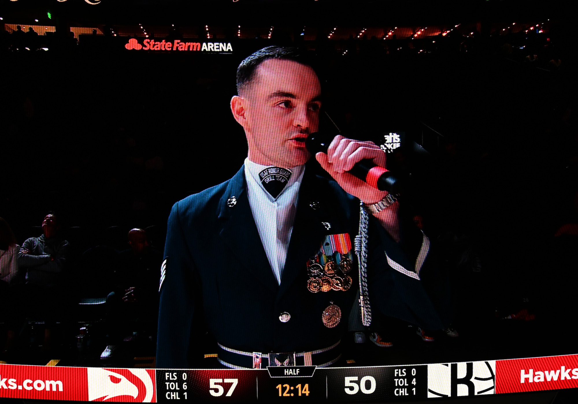 A jumbotron shows U.S. Air Force Staff Sgt. William Douglass, a ceremonial guardsman assigned to the U.S. Air Force Honor Guard Drill Team, while he emcees a Drill Team performance during an NBA halftime show in Atlanta, Ga., March 12, 2026. During the event the Drill Team performed in front of approximately 16,000 guests and emphasized the team mission of connecting with audiences and inspiring the next generation of service members through precision and excellence. (U.S. Air Force photo by Tech. Sgt. Sergio A. Gamboa)