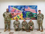 Volunteers pose in front of the 55th Medical Group's new mural located in the Heritage Hall at the Ehrling Bergquist Clinic, Mar. 17, 2026. More than 10 volunteers from across the clinic collaborated to complete the painting.