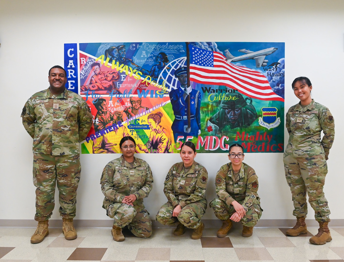 Volunteers pose in front of the 55th Medical Group's new mural located in the Heritage Hall at the Ehrling Bergquist Clinic, Mar. 17, 2026. More than 10 volunteers from across the clinic collaborated to complete the painting.