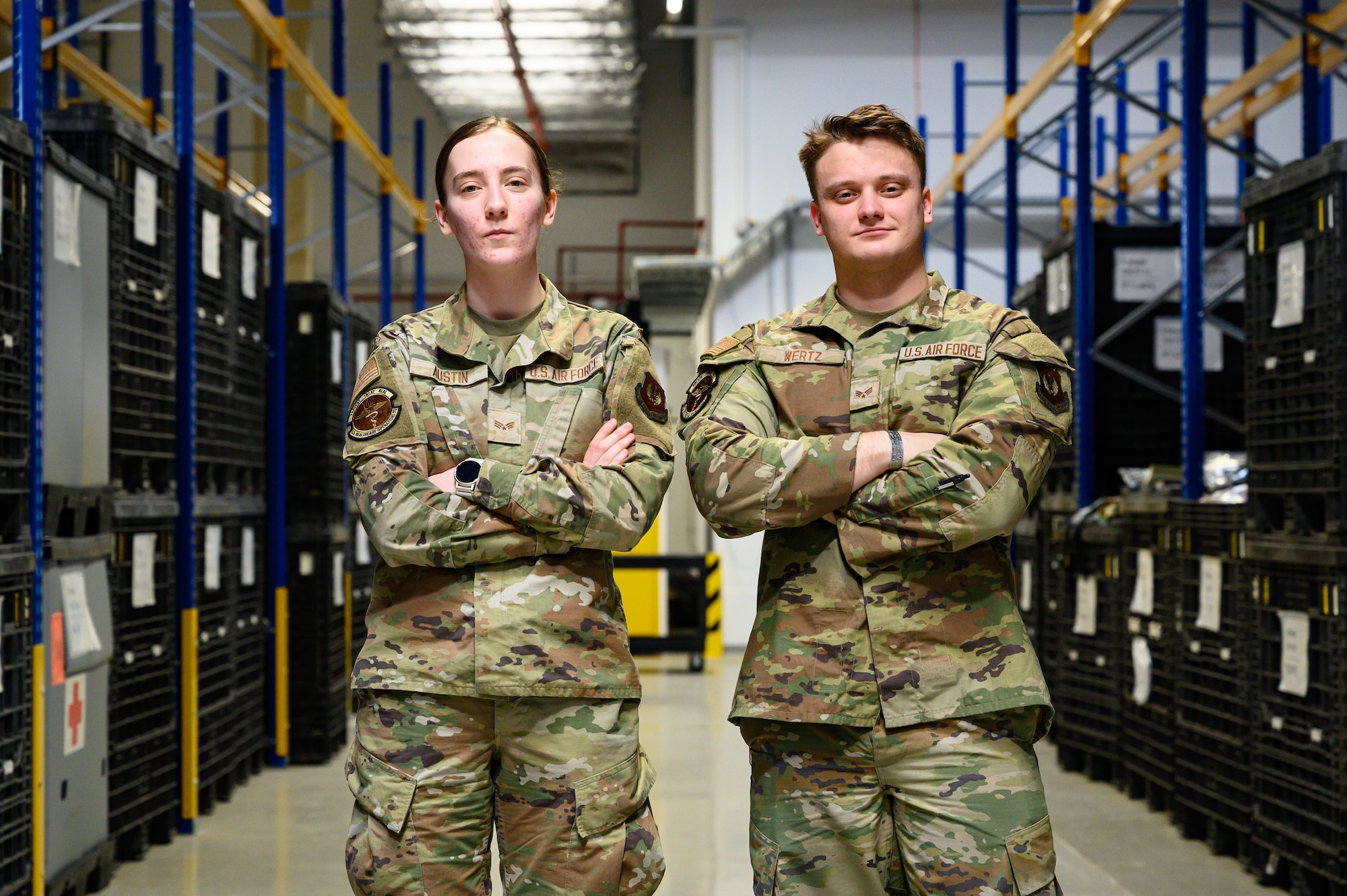 Two people pose for a photo inside a warehouse.