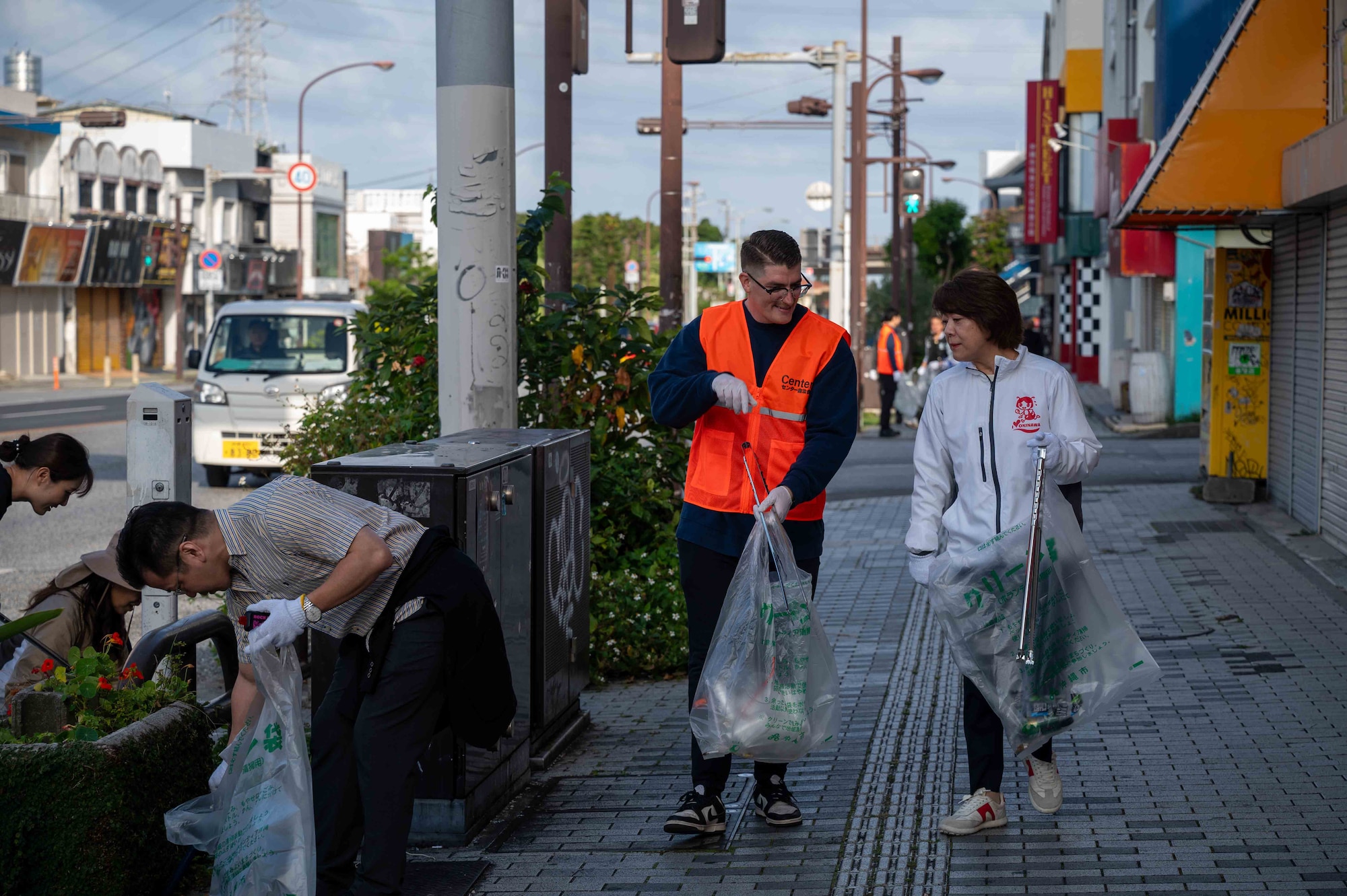 a volunteer and a civic leader hold trash bags while walking down the street