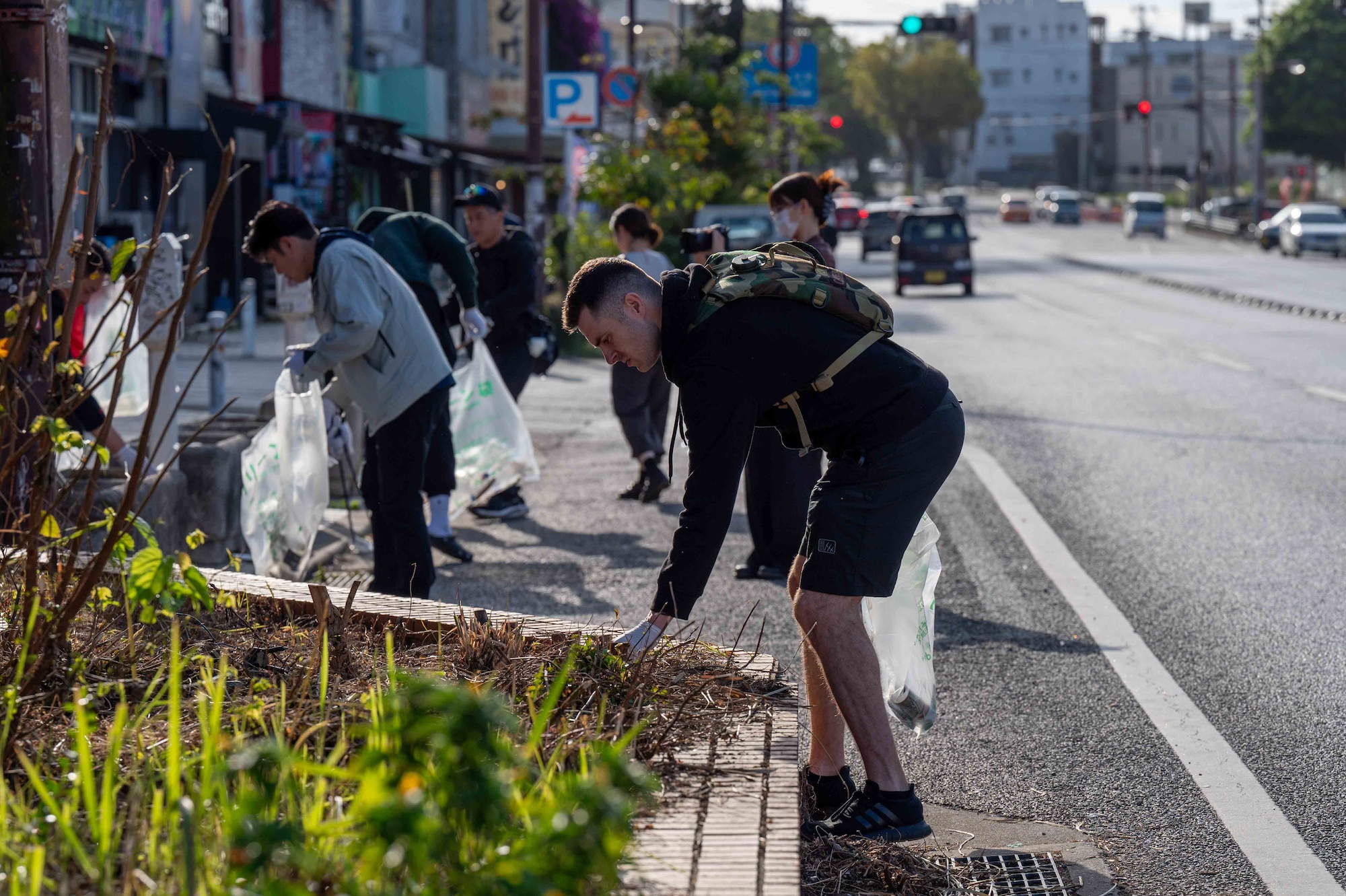 volunteers picking up trash on the side of the road while holding a trash bag