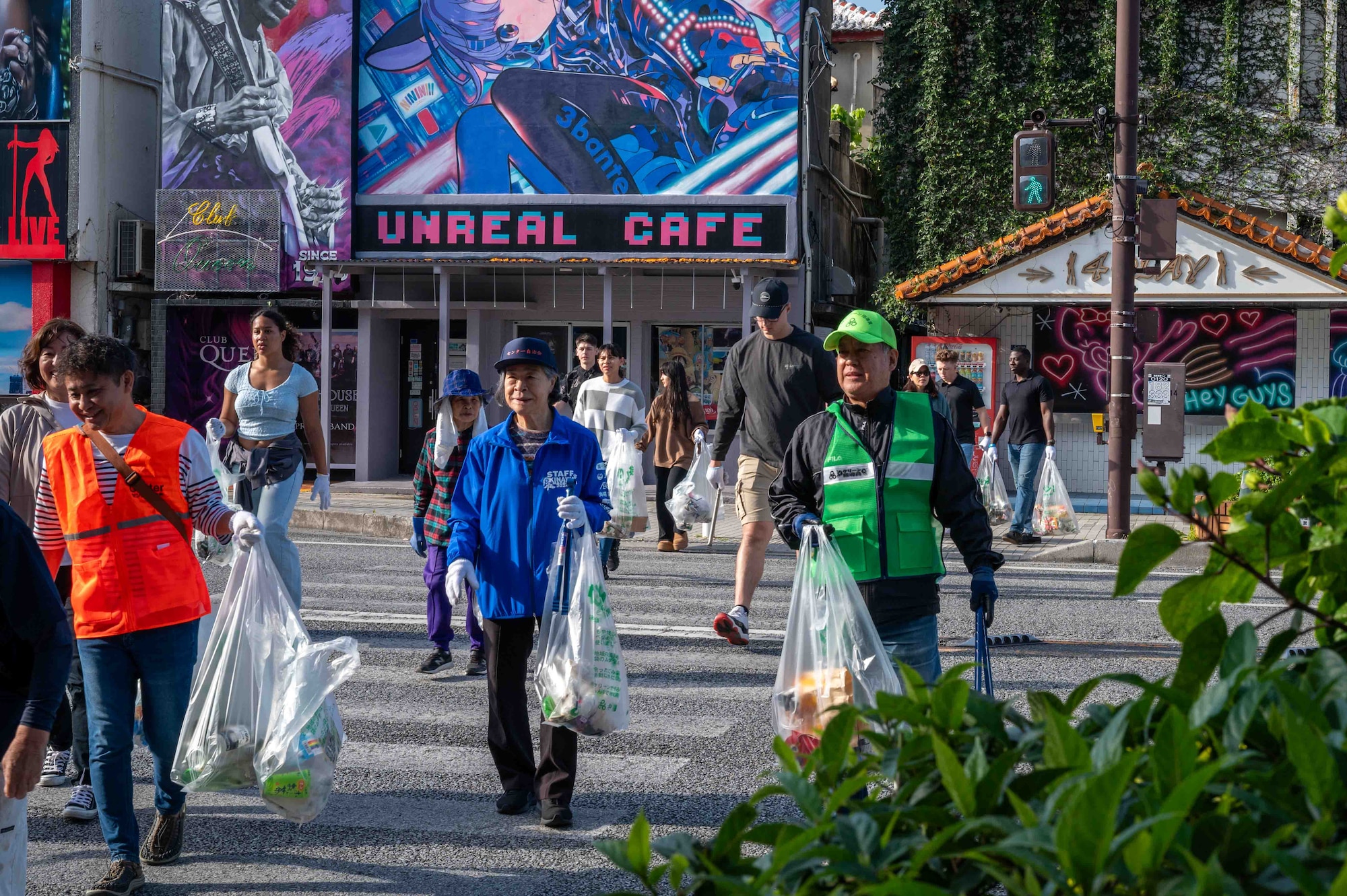 volunteers carry trash bags while crossing the street