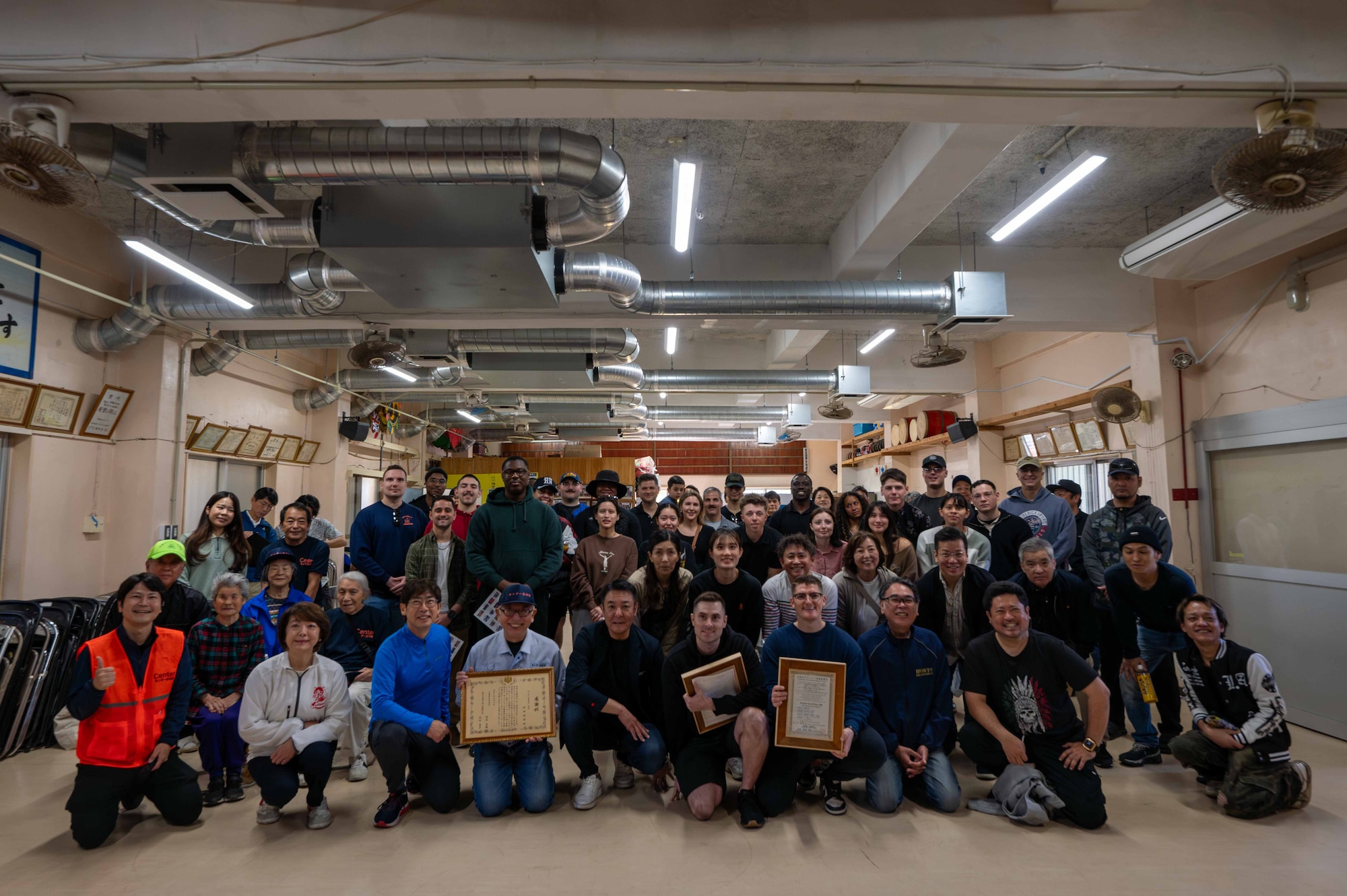 A group of people huddled together for a photo with certificates