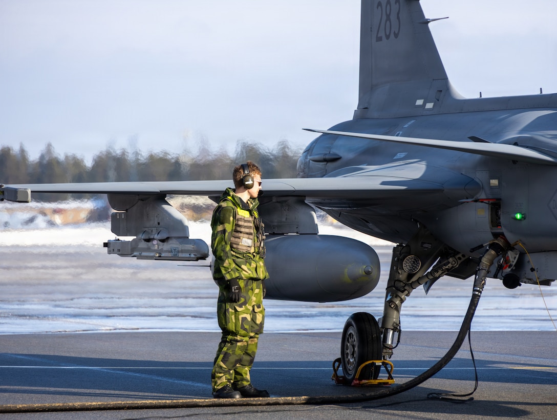 Swedish Army Pvt. Edvin Andersson, a mechanic with 32nd Intelligence Battalion, monitors the fuel valve on a JAS-39 Gripen aircraft assigned to the Norrbotten Air Wing, F 21, at Kallax Air Base, Luleå, Sweden, March 12, 2026. Marine Wing Support Squadron (MWSS) 273, Marine Air Control Group 28, 2nd Marine Aircraft Wing, conducted forward arming and refueling point operations alongside the 32nd Intelligence Battalion to support NATO air operations during exercise Cold Response 26. A key component of NATO's enhanced vigilance activity Arctic Sentry, exercise Cold Response 26 is a Norwegian-led winter military exercise designed to enhance collective defense capabilities and ensure U.S. readiness to rapidly deploy and seamlessly operate alongside NATO Allies in challenging arctic conditions. Andersson is a native of Luleå. (U.S. Marine Corps photo by Lance Cpl. Donovan Pimentel)